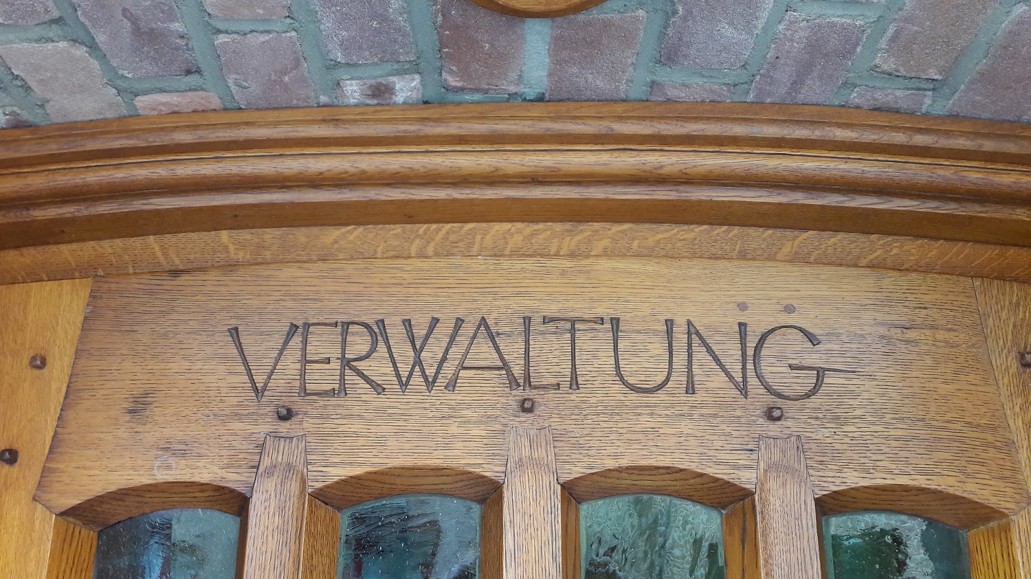 Das Bild zeigt den Schriftzug "Verwaltung" über der Tür des Nebeneingangs zum historischen Rathaus.