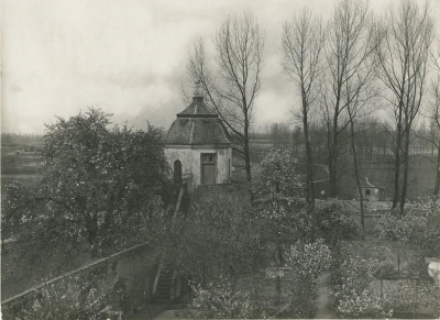 Taubenturm, Foto: E. Steiger, 1926 Foto des Taubenturms über einen Garten mit blühenden Bäumen und Sträuchern hinweg mit niederrheinischer Landschaft im Hintergrund