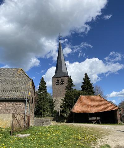Blick auf den Turm der St. Antonius Kirche Hanselaer über einen windschiefen Wagenschuppen hinweg