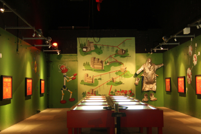 Ausstellungsraum des Brütermuseums im Wunderland Kalkar mit Schautafeln an grün gestrichenen Wänden und zehn Vitrinen in der Raummitte