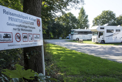 Foto vom Reisemobilstellplatz Kalkar mit Hinweisschild und einigen Wohnmobilen auf Rasenplätzen
