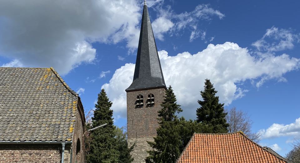 Blick auf den Turm der St. Antonius Kirche Hanselaer über einen windschiefen Wagenschuppen hinweg