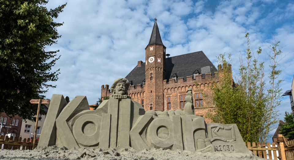Sandskulptur mit Schriftzug Kalkar vor dem historischen Rathaus von Kalkar