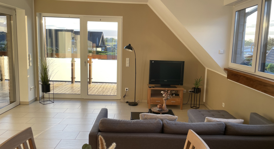 Ferienwohnung Am Pappelwäldchen, Blick vom Esstisch über die Sitzgruppe auf die Balkontüre