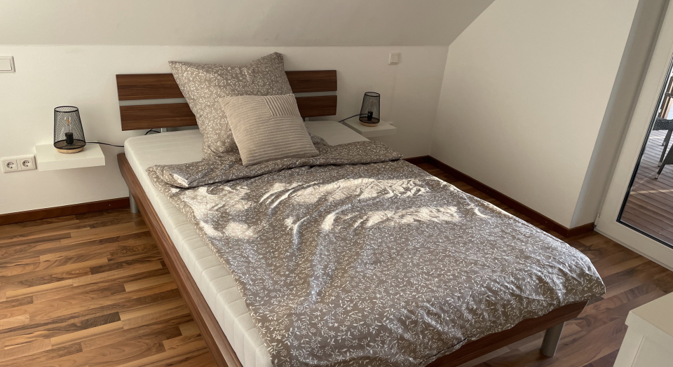 Ferienwohnung Am Pappelwäldchen,  Blick auf das Doppelbett unter einer Dachschräge im Schlafzimmer
