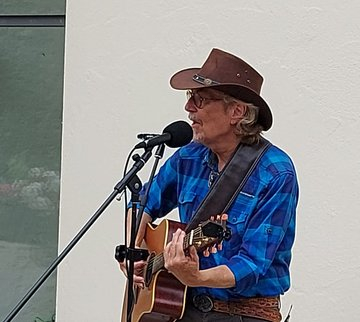Der Sänger "Mr. Bluebird" mit Hut und Gitarre vor einem Mikrofon bei einem Auftritt in der Burg Boetzelaer in Kalkar-Appeldorn