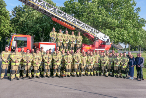 Mitglieder der Freiwilligen Feuerwehr Kalkar mit ihrer neuen Einsatzkleidung vor und auf einem Feuerwehrfahrzeug