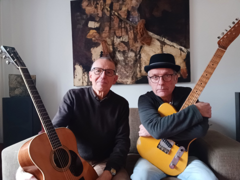 Foto der Musiker Klaus Willwacher und Friedhelm Körner, die, auf einem Sofa sitzend, jeweils eine Gitarre in der Hand halten